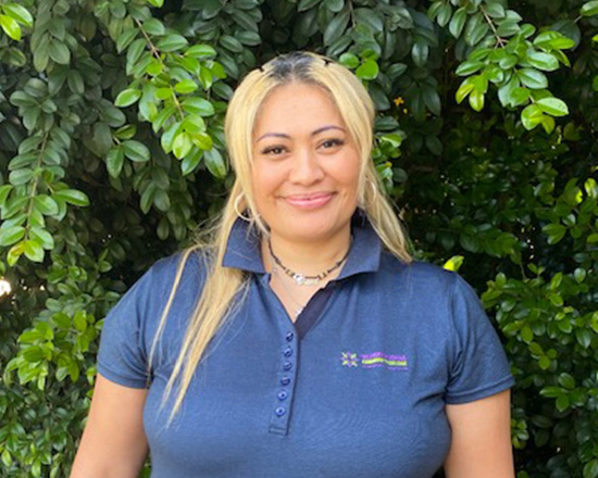 Profile of Kiani Abera. Woman stands in front of tree with long blonde hair